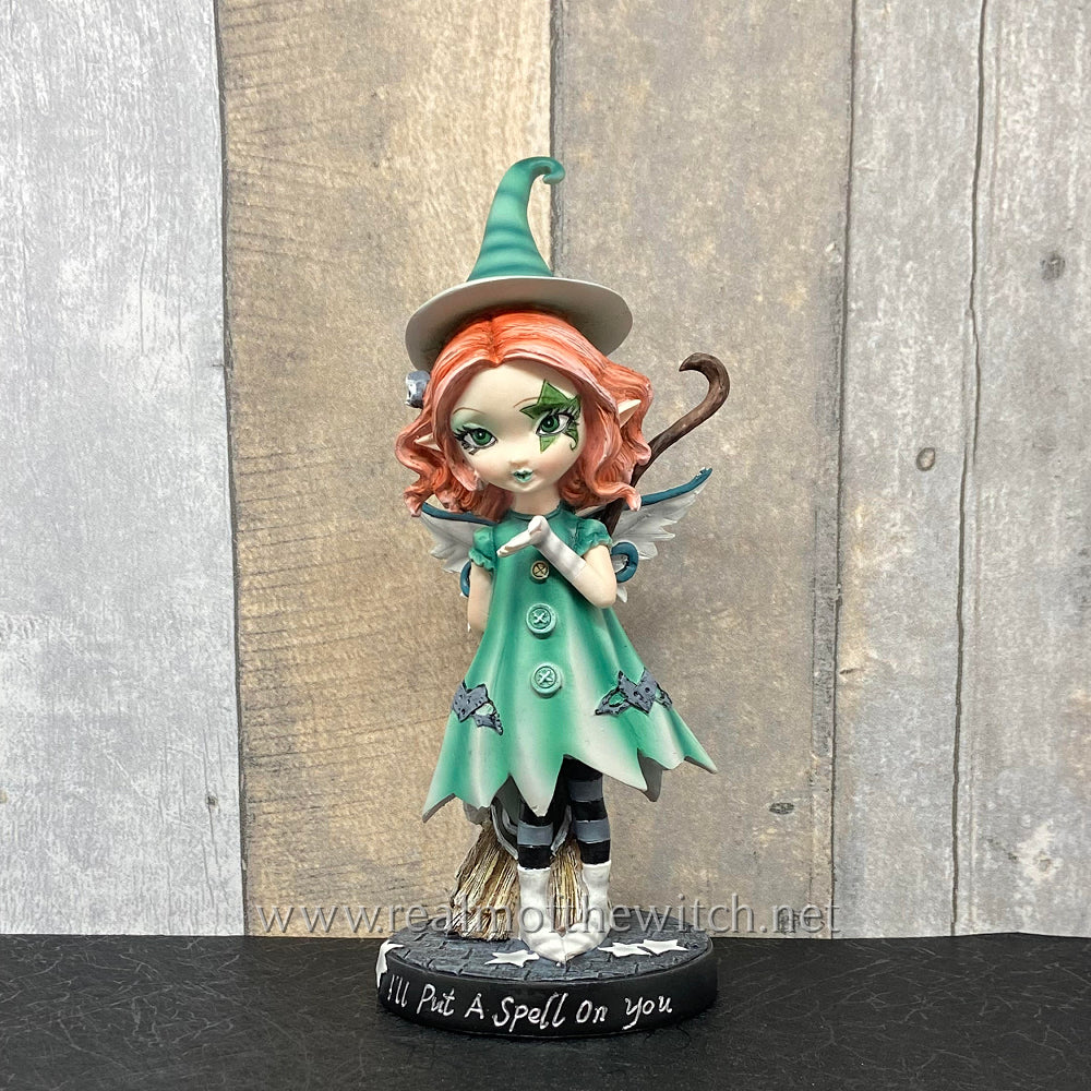 Wearing a turquoise dress and pointed hat, this unique fairy has a pair of delicate white wings emerging from her back.  Her light auburn hair frames her face which is decorated by a large star. In her hand, she holds a broomstick while spreading a little magic with the other. The theme behind the figurine is emblazoned on the black base, 'I'll Put A Spell On You'.